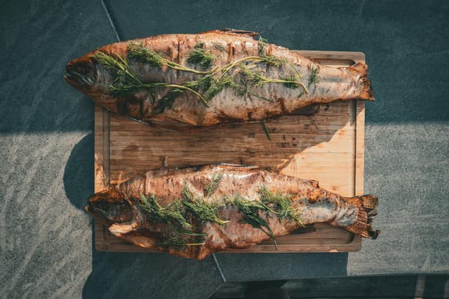 Two grilled fish on a cutting board.