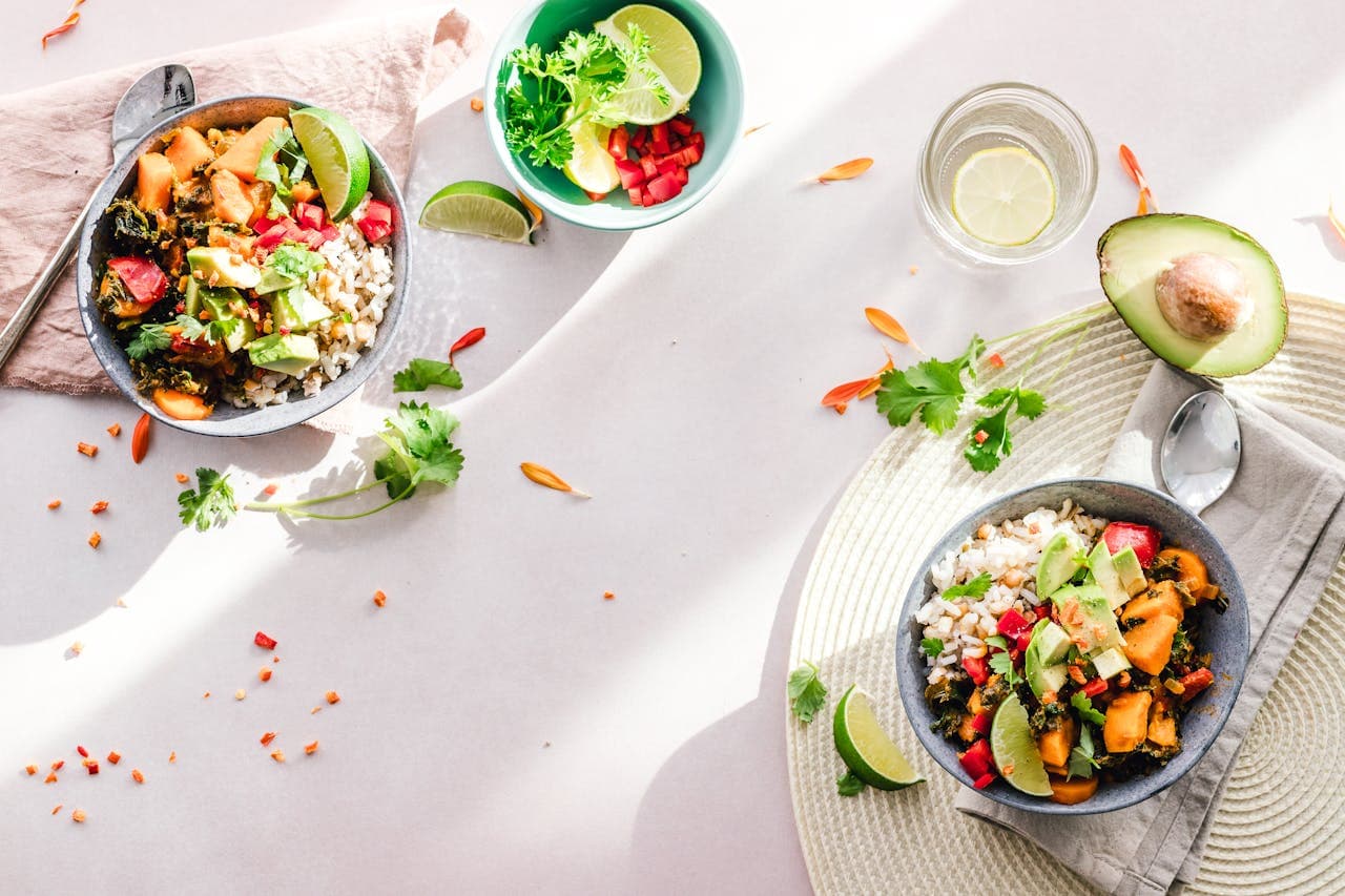 A healthy meal for two consisting of avocado, rice, lemon, and fruits.